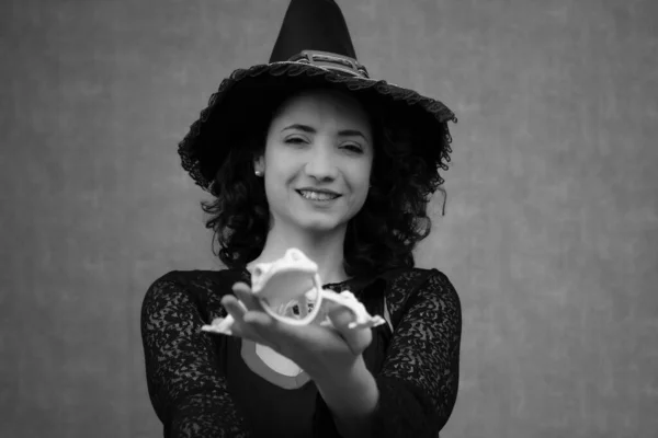 Siyah beyaz, dost canlısı cadının gülümsemeli bir kurbağa iskeletini tutarken çekilmiş portresi. Cadılar Bayramı kutlaması için mükemmel, cadılık, peri masalı ve fantezi teması. Arkaplanda boşluk kopyala.