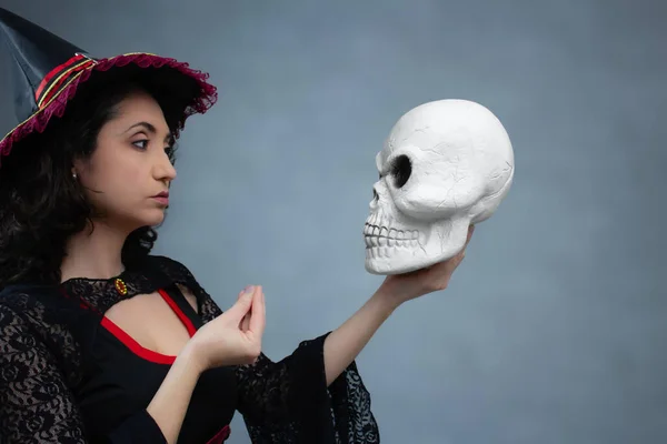 Komik cadı bir kafatasıyla konuşuyor ve İtalyan el hareketi yapıyor. Cadılar Bayramı için mükemmel, ürkütücü komedi, cadılık ve sihirbazlık. Kopya alanı ile yatay stüdyo portresi.