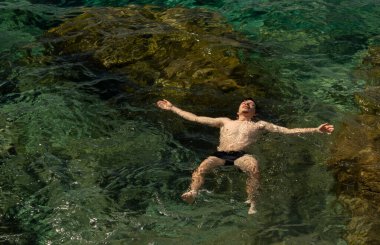 Yazın Akdeniz 'in berrak sularında kolları açık ve gözleri kapalı yüzen bir adamın en iyi görüntüsü, özgürlük, rahatlama ve açık hava keyfi.