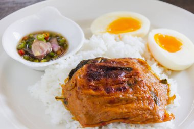 Sıcak pilav üzerine köri ezmeli balık buğulama ve beyaz tabakta balık soslu acılı yumurta.