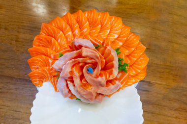 Somon dilimleri, restorandaki beyaz kasede buzun üzerinde pasta şeklinde süslenmişti.