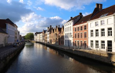 Güneşli bir günde güzel ortaçağ renkli evler, köprü ve yansımaları ile Bruges kanalının manzara şehir görünümü.