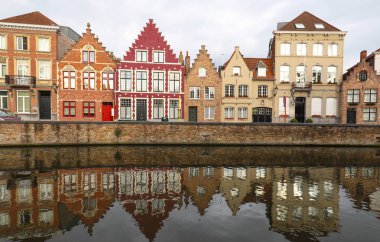 Güneşli bir günde güzel ortaçağ renkli evler, köprü ve yansımaları ile Bruges kanalının manzara şehir görünümü.