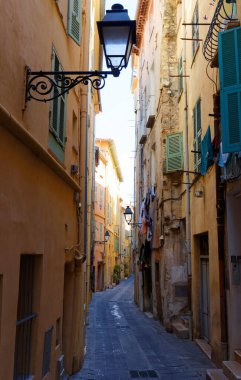 Fransa 'nın güneyindeki Menton şehrinin tarihi merkezinde taş evleri ve renkli cepheleriyle dar bir sokak.