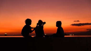 Gün batımında çocukların siluetleri, Manila sahil, Filipinler