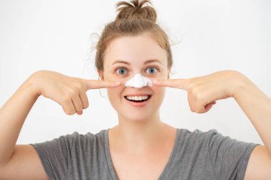 Burun üzerinde beyaz soyma maskesi ile genç beyaz kadın, siyah başlıkları kaldırma