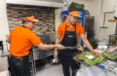 Manila, Filipinler-Temmuz, 26, 2016: Iki genç erkek Manila bir filipino restoran mutfakta gıda hizmet