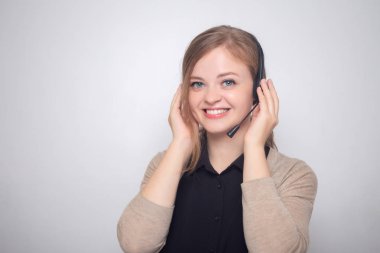 Bir çağrı merkezinde kulaklık telefonu ile mutlu gülümseyen Genç beyaz kadın