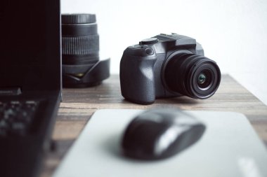 Fotoğrafçı veya stok fotoğrafçılık konsepti, masa iş istasyonunda dizüstü bilgisayarın yanında dijital siyah kamera