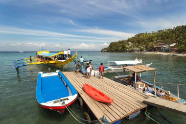 Sabang, Puerto Galera, Filipinler - 13 Ocak 2017: İskele denizi, mavi gökyüzü, palmiyeler ve tekneler. popüler turist ve dalış noktası.