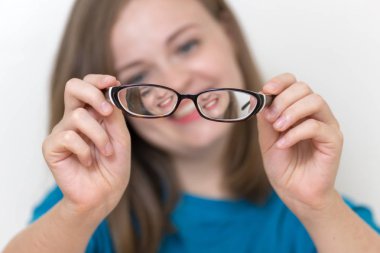 Young caucasian woman holds glasses in hands, bad sight