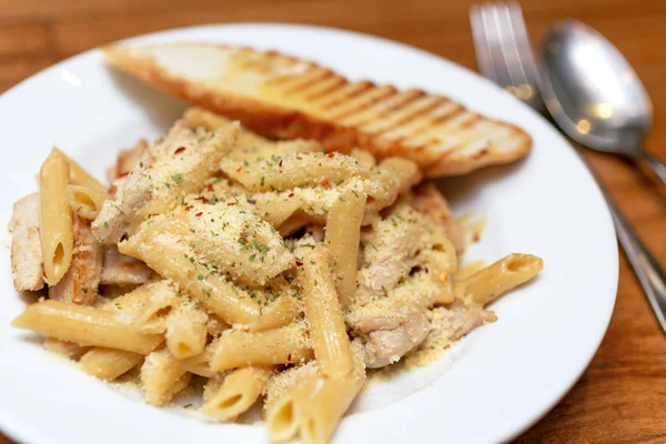 Authentic Italian creamy chicken Alfredo penne pasta in a restaurant closeup