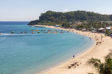 Puerto Galera, Filipinler - 4 Nisan 2017: Deniz, mavi gökyüzü, palmiyeler, turistler ve tekneler White Beach, Sabang.