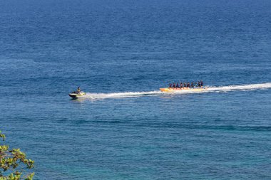 Puerto Galera, Filipinler - 4 Nisan 2017: Denizde jet ski süren bir adam, White Beach yakınlarında muz teknesinde insanlar