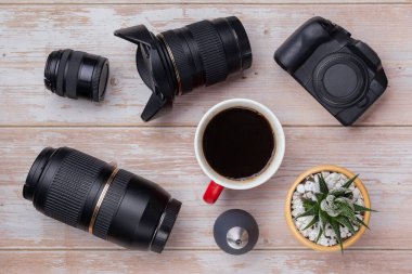 Ahşap masaüstü arka planında düz fotoğraf makinesi yatağı: dslr kamera ve lens. Fotoğrafçı çalışma alanı konsepti. Üst görünüm