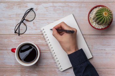 El yazısının üstü boş sarmal defterde kalemle notlar alıyor.. 