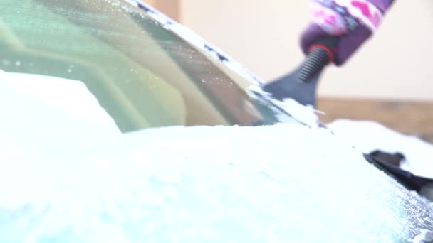 Женщина моет окно машины от снега и льда скребком — стоковое видео