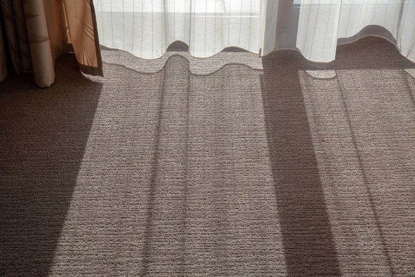 Η σκιά στο χαλί στο δωμάτιο. Ο ήλιος λάμπει μέσα από τις κουρτίνες στο δωμάτιο — Φωτογραφία Αρχείου