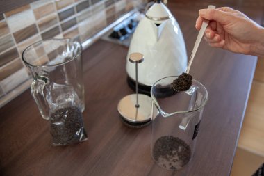 Mutfaktaki kadın güzel kokulu çay yaprakları hazırladı. Susayınca kaynar su karıştırır.