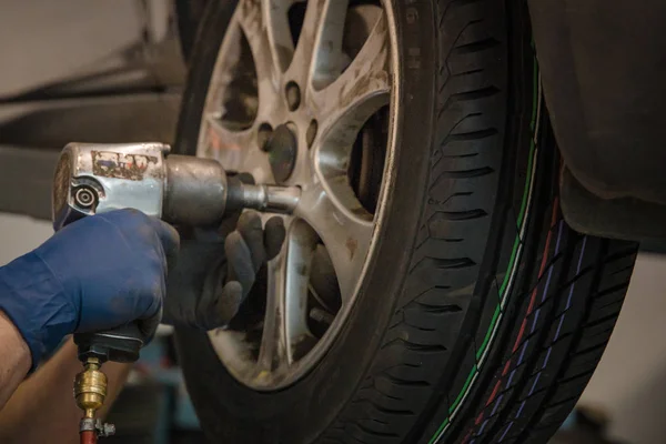 Byta vinterdäck på sommardäck i ett professionellt garage med hjälp av professionella verktyg. bil på ett hydrauliskt uttag — Stockfoto