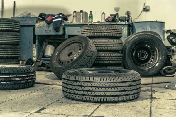 Sustitución de neumáticos de invierno en neumáticos de verano en un garaje profesional con la ayuda de herramientas profesionales. coche en un gato hidráulico — Foto de Stock