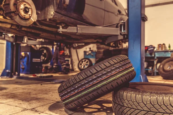 Byta vinterdäck på sommardäck i ett professionellt garage med hjälp av professionella verktyg. bil på ett hydrauliskt uttag — Stockfoto