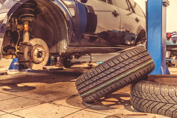 在专业工具的帮助下，在专业车库更换夏季轮胎上的冬季轮胎。液压千斤顶上的汽车 — 图库照片