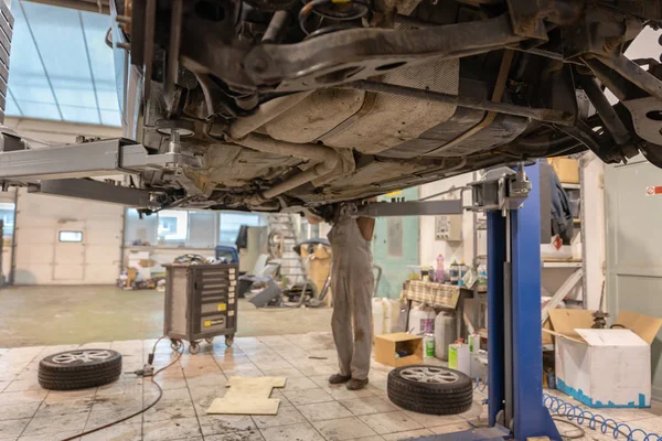 Reparera och kontrollera bilen i reparationsverkstad. En erfaren tekniker reparerar den defekta delen av bilen. Jag byter däck — Stockfoto