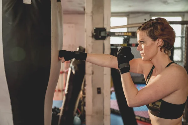 Gorgeous woman, mma fighter in gym during training. Preparing for a hard caged match