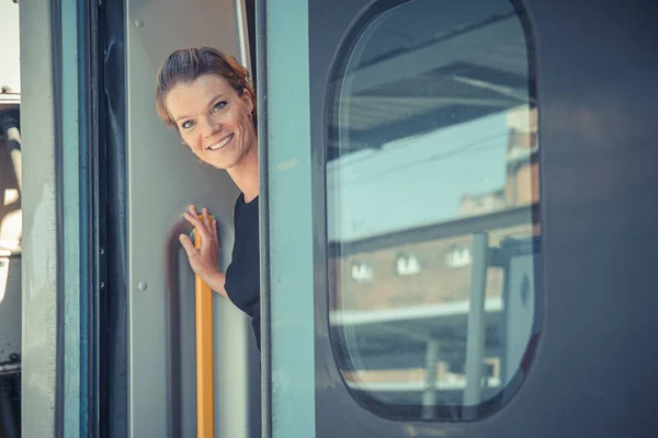 Joven mujer atractiva hombre de negocios dice adiós a un huésped en tren. Entra en el tren internacional con su equipaje — Foto de Stock