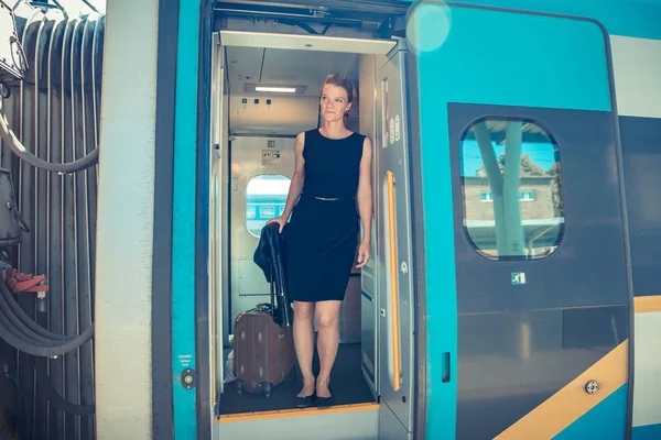 Молодая привлекательная женщина-бизнесмен прощается с жильцом поезда. Он садится на международный поезд со своим багажом. Лицензионные Стоковые Фото