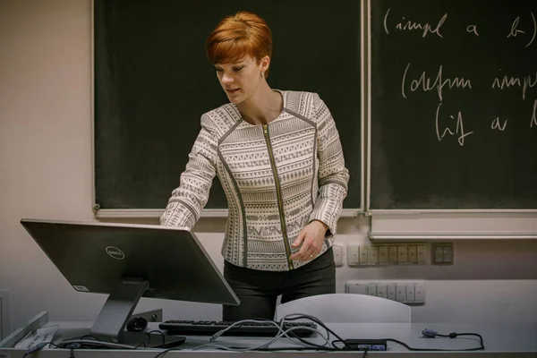 Ung kvinna lärare i College. Undervisning i ett universitets klassrum. Blackboard beskrivs av krita. Projicering från dataprojektorn — Stockfoto