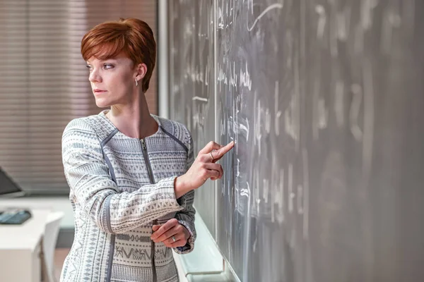 Ung kvinna lärare i College. Undervisning i ett universitets klassrum. Blackboard beskrivs av krita. Projicering från dataprojektorn — Stockfoto