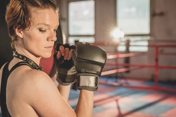 Young woman prepares for matches MMA in the cage. Training in a sport hall