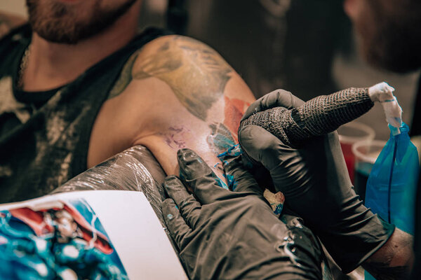 изготовление цветных татуировок в салоне, иглы на коже
