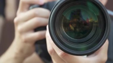 Genç adam fotoğraf ve video çekmek için profesyonel bir kamera kullanıyor. büyük yakınlaştırma lensi