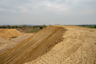 Kazıcı, yaz mevsiminde inşaat alanındaki toprağı özetliyor