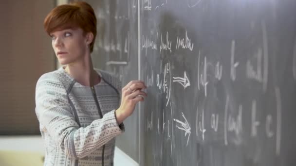 Młody nauczyciel wykłada w Szkole Matematyki, pisze kredę na tablicy — Wideo stockowe