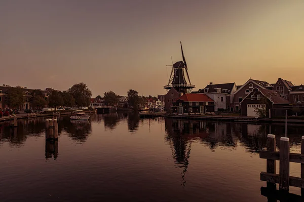 Båt ankrad på en kanal i Amsterdam vid soluppgången, väderkvarn — Stockfoto
