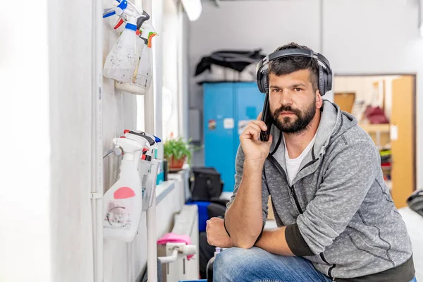 Téléphone homme avec casque sur la tête dans un atelier de réparation automobile — Photo