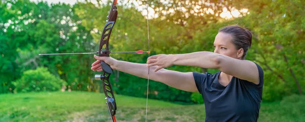 Tiro con l'arco in natura, giovane donna che punta una freccia contro un bersaglio — Foto Stock