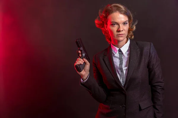 Business woman with a gun in his hand. portrait on a black background. copy space — Stock Photo, Image