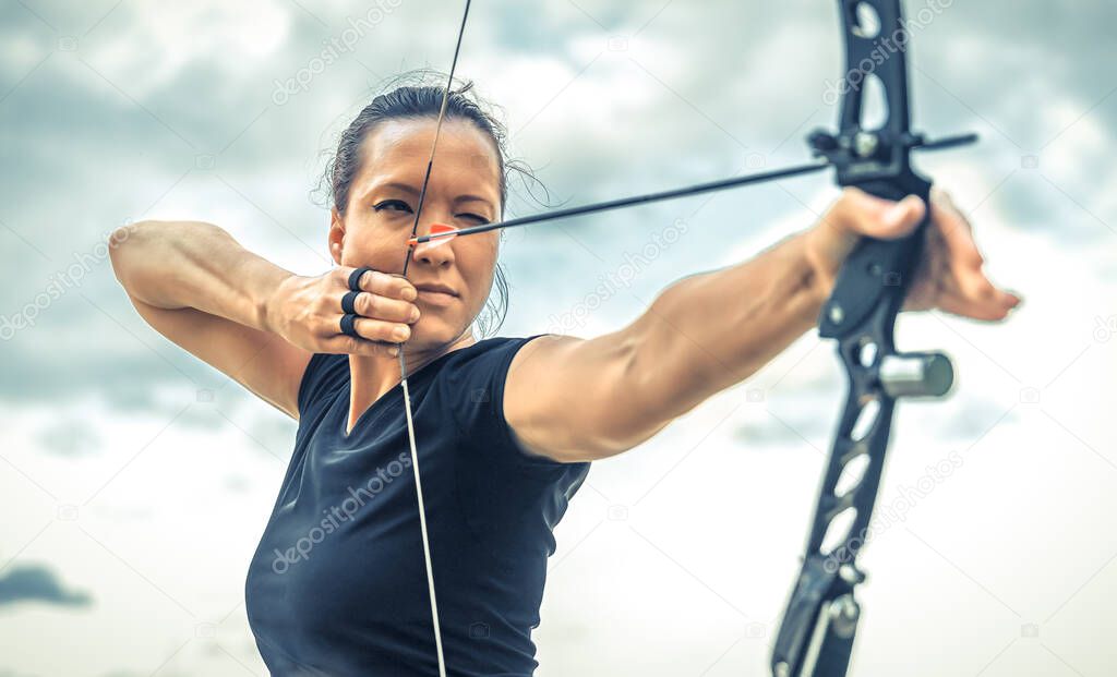 attractive woman on archery, focuses eye target for arrow from bow.