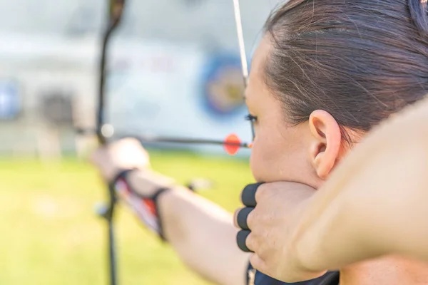 Tiro con arco, mujer joven con una flecha en un arco centrado en golpear a un objetivo —  Fotos de Stock