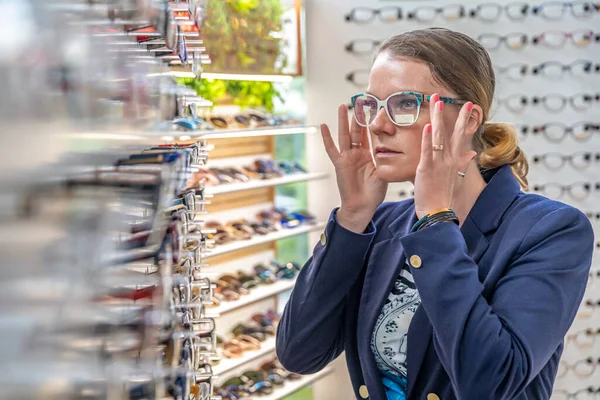 一位年轻迷人的女士在一家光学商店里试戴新眼镜。复制空间 — 图库照片