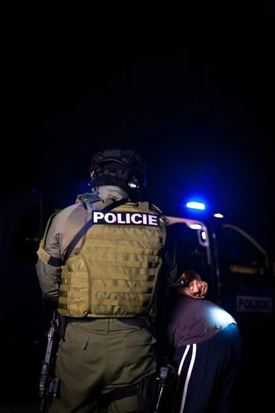 Un policier met des menottes sur les mains d'un criminel lors d'une arrestation. Voiture de police avec phares clignotants — Photo