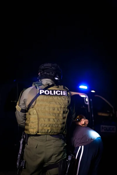 一名警察在逮捕罪犯的时候给他戴上手铐.有闪光灯塔的警车 — 图库照片