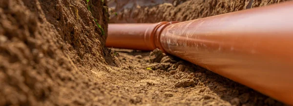 Kunststof buizen in de grond tijdens de bouw van een gebouw, bunner met kopieerruimte — Stockfoto