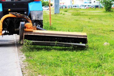 Meme kentsel çimenler üzerinde çim mows bir traktör. kaldırım ve kaldırım yakın çim kesme