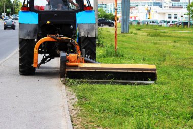 Meme kentsel çimenler üzerinde çim mows bir traktör. kaldırım ve kaldırım yakın çim kesme